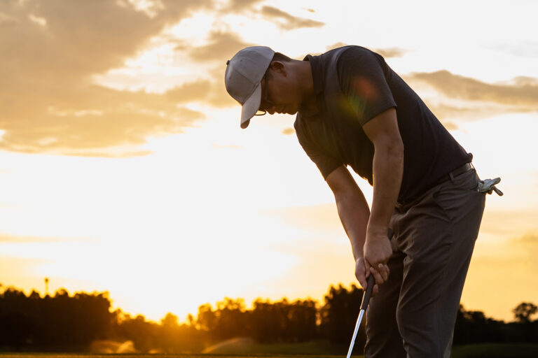 Professional,young,male,golfer,swings,his,club,on,scenic,golf