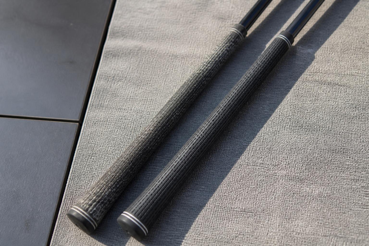 detail of a worn golf grip alongside a fresh new grip on graphite shafts laid on a neutral gray mat