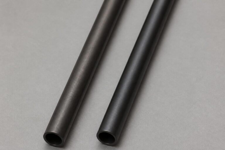 bright even studio lighting. Two iron shafts with slightly different dark finishes laid side by side on a clean gray backdrop
